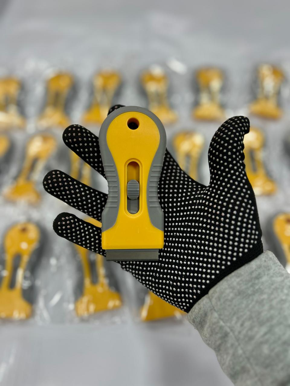 Raspador plástico amarillo  con cuchilla metálica para limpieza de adhesivos