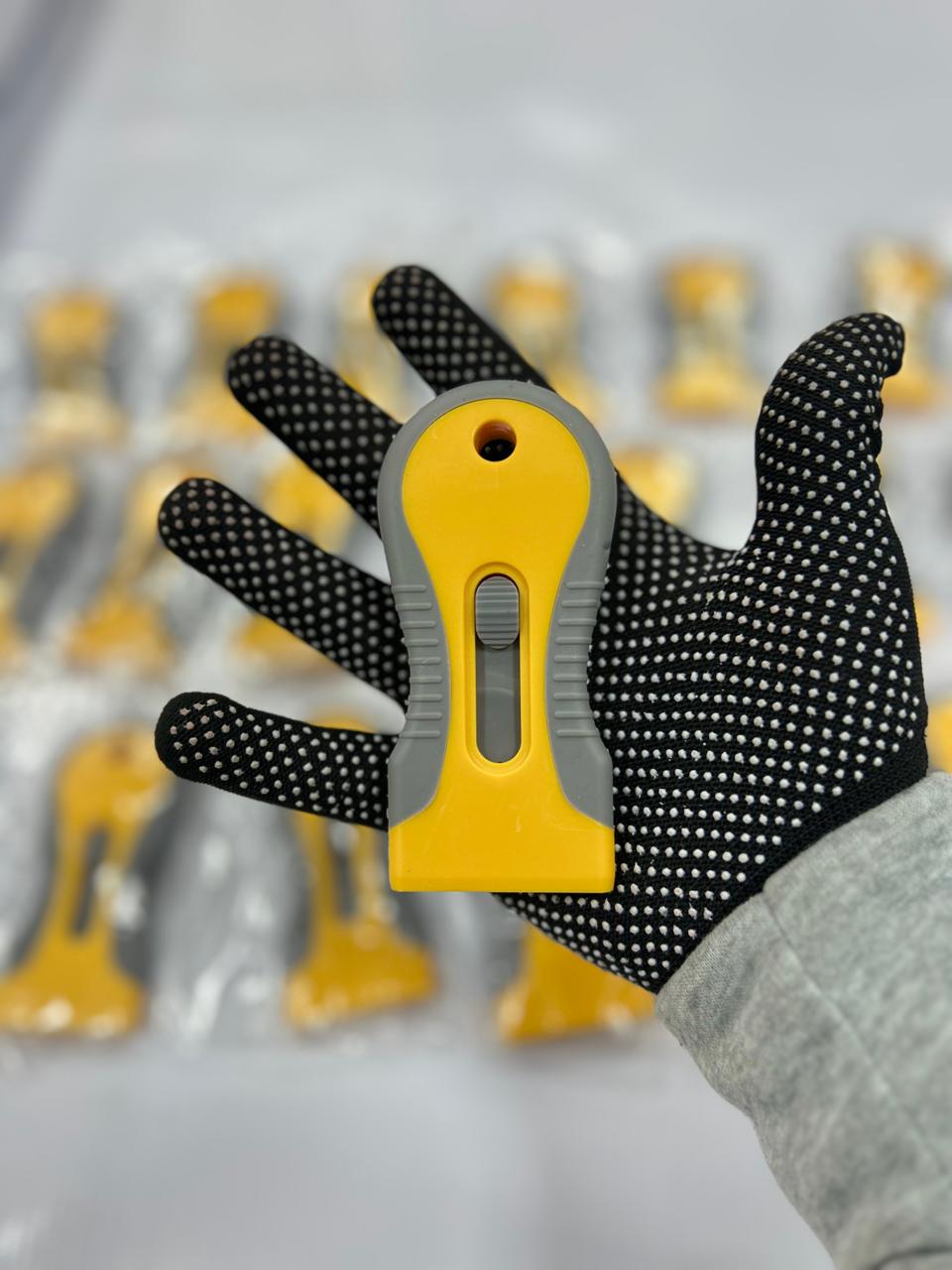 Raspador plástico amarillo  con cuchilla metálica para limpieza de adhesivos